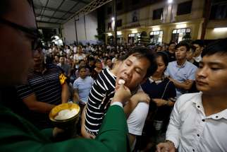 A priest distributes Communion during Mass Aug. 27 at a church in Hanoi, Vietnam. 