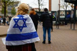 A woman wrapped in an Israel flag stands outside the place where mayor of Amsterdam Femke Halsema attends a press conference following the violence targeting fans of an Israeli soccer team, in Amsterdam, Netherlands, Nov. 8, 2024.