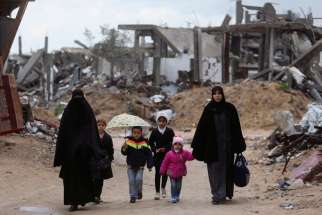 Palestinians walk near the ruins of houses Feb. 20 that witnesses said were destroyed or damaged by Israeli shelling during a 50-day war last summer, near Gaza City. Six months after the end of the most recent war in Gaza, one aid official said there is still a &quot;grave humanitarian crisis.&quot;