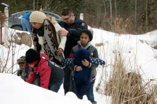  A woman who told police that she and her family were from Sudan is taken into custody by a Royal Canadian Mounted Police officer after arriving Feb.12 by taxi and walking across the U.S.-Canada border into Quebec.