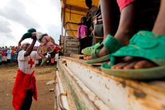 A Congolese refugee girl is helped off a truck near the border town of Gisenyi, Rwanda, in this 2012 file photo. Armed men kidnapped two Catholic priests in the troubled North Kivu province July 16.