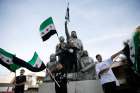 People celebrate next to a sculpture of Sultan Pasha al-Atrash, a Druze warrior who led a revolt against French rule in 1925, after Syrian rebels announced that they had ousted President Bashar Assad, in Majdal Shams, a Druze village in the Israeli-controlled Golan Heights, Dec. 9, 2024.