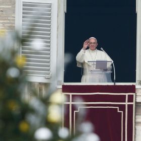 The Christmas tree is seen as Pope Francis greets the crowd as he leads the Angelus from the window of his studio overlooking St. Peter&#039;s Square at the Vatican Dec. 22.