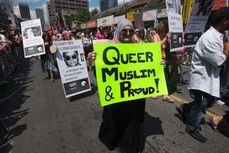 A woman carrying a sign that reads, &quot;Queer, Muslim and Proud&quot; marches during the Gay Pride parade in Toronto on July 1, 2012. 