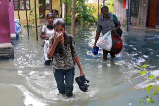 Residents carry their belongings as they evacuate their home Dec. 2 after flooding caused by Typhoon Ockhi in the coastal village of Chellanam in the southern state of Kerala, India. The storm claimed the lives of at least 32 poor Catholic fishermen who were at sea and 200 more were missing. 