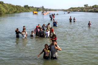 A caravan wades past buoys, being constructed to deter migrant crossings through the Rio Grande, as they search for an entry point into Eagle Pass, Texas. Post-COVID, the numbers of trafficking victims identified by the UN has risen by 25 per cent.