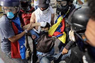 A group of demonstrators tries to help 22 year-old David Jose Vallenilla after he was shot by a Venezuelan military police sergeant June 22 in Caracas. Vallenilla later died from his wounds, bringing to 76 the total number of people killed in the protests.
