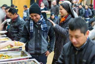 A nun shares a light moment with a man during a meal following a Dec. 17 Mass for migrant workers at Our Lady of Sorrows Church in Vancouver, British Columbia.
