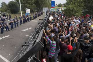 Migrants stand in front of a barrier at the border with Hungary near the village of Horgos, Serbia, on Sept. 16, 2015.