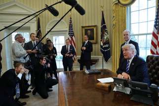 U.S. President Donald Trump talks to journalists in the Oval Office at the White House March 24. After the Senate released its health care bill June 22, the Congressional Budget Office said the measure would leave 22 million more people uninsured.