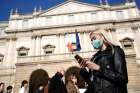 A woman wearing a face mask checks her phone outside the Teatro alla Scala opera house, closed by authorities due to a coronavirus outbreak in Milan Feb. 24, 2020. The Archdiocese of Milan issued a notice Feb. 23 suspending all public celebrations of Mass until further notice in compliance with Italian Ministry of Health precautions to prevent the further spread of the coronavirus.