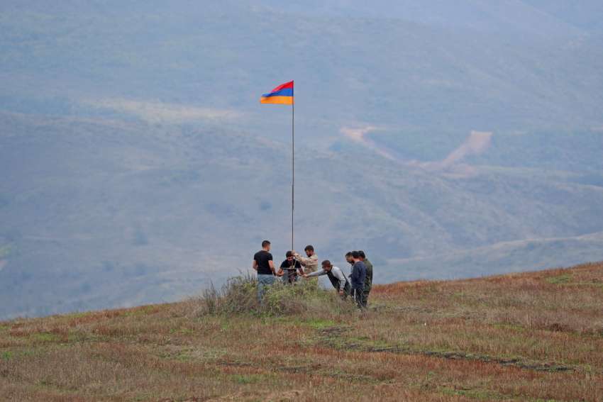Men install an Armenian flag next to a checkpoint on the road leading to Artsakh near the border village of Kornidzor, Armenia, Sept. 22, 2023.