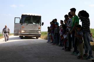 Immigrants turn themselves in to Border Patrol agents April 2 after illegally crossing the border from Mexico into the U.S., and wait to be transported to processing center near McAllen, Texas.