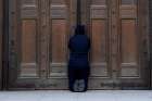 A person prays at the closed doors of London&#039;s Westminster Cathedral on Easter, April 12, 2020, during the COVID-19 pandemic. Churches in England and Wales must wait until July before they may reopen under a coronavirus recovery strategy published by the government.