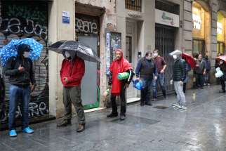 People wait in line for free food outside the Church of Santa Anna in Barcelona, Spain, April 21, 2020, during the COVID-19 pandemic. The parish publishes a daily tally of meals and hygiene equipment handed out to needy recipients, as well as a blog with advice for surviving the crisis.