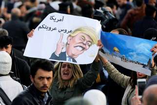  Protesters near the U.S. embassy in Amman, Jordan, hold a lampoon of President Donald Trump Dec. 7. The cartoon reads, &quot;America is the Arab leader.&quot;
