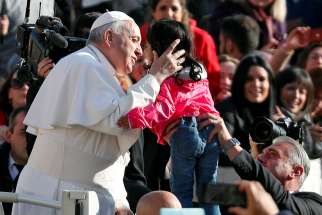 Pope Francis embraces a child as he arrives to lead the weekly general audience in St. Peter&#039;s Square at the Vatican Nov. 14. 