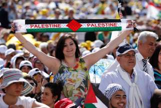 A woman holds a banner with the colors of the Palestinian flag before the start of the canonization Mass for four new saints celebrated by Pope Francis in St. Peter&#039;s Square at the Vatican May 17. 