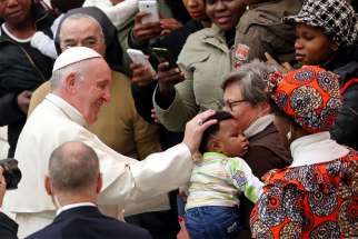 Pope Francis greets a child as he arrives to lead his general audience in Paul VI hall at the Vatican Dec. 19.