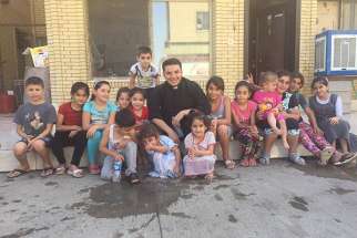 The Rev. Martin Banni with a group of displaced children from the Christian towns in Nineveh in Irbil. Banni spent much time playing with children and telling them stories from the Bible.