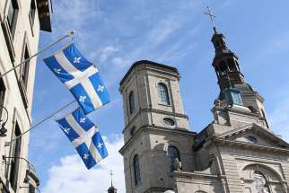 Quebec provincial flags are displayed outside a building across the street from the Cathedral-Basilica of Notre-Dame de Quebec in Quebec City Oct. 5. 