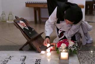  A nun lights a candle next to a photograph of Bishop Pierre Claverie at his grave in St. Mary&#039;s Cathedral, where a vigil was held in Oran, Algeria, Dec. 7