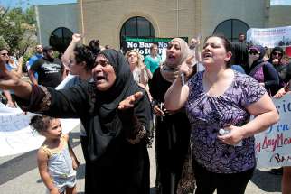 Women react as they talk about family members who were arrested by immigration officials during a June 12 rally outside the Mother of God Chaldean Catholic Church in Southfield, Mich. Dozens of Chaldean Christians were arrested by federal immigration officials over the weekend of June 10 and 11 in the Detroit metropolitan area, which members of the local church community said left them feeling sad and frustrated.