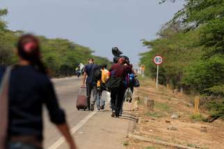Venezuelans walk on a highway in Paraguachon, Colombia, after crossing the border from Venezuela Feb. 16. Colombian bishops are calling on officials, parishes and the international community to increase efforts to help Venezuelan migrants, who are leaving their country at the rate of at least 50,000 people per month. 