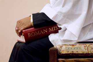 An altar server holds a copy of the Roman Missal during Mass.