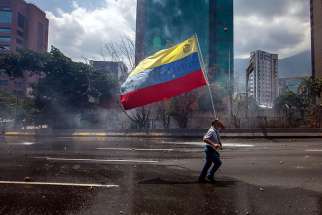A demonstrator carries Venezuela’s flag in Caracas, Venezuela, April 26. After meeting with government representatives, Venezuela&#039;s bishops conference reiterated its rejection of government proposal to draft a new constitution.