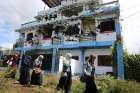  Residents who returned from evacuation centres walk past a bullet-ridden house Oct. 29, 2017, believed to have been used by pro-Islamic State militant group leaders in Marawi, Philippines. 