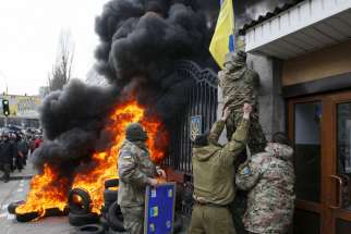 Servicemen from the Aydar battalion throw a Ukrainian flag from the building of Ukraine&#039;s Defense Ministry in Kiev during a protest against the disbanding of the battalion in this Feb. 2 file photo. 