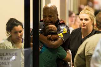 A Dallas police officer is comforted July 7 at Baylor University Hospital&#039;s emergency room entrance after a shooting attack. Snipers shot and killed five police officers and wounded seven more at a demonstration in Dallas to protest the police killing of black men in Baton Rouge, La., and a suburb of St. Paul, Minn. Two civilians also were injured in Dallas.
