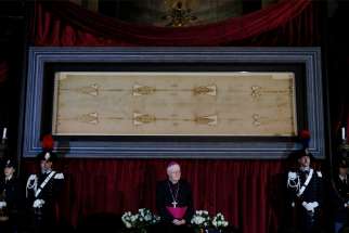 Archbishop Cesare Nosiglia of Turin, papal custodian of the Shroud of Turin, stands in front of the shroud during a preview for journalists in the Cathedral of St. John the Baptist in Turin, Italy, April 18. A public exposition of the shroud, believed by many to be the burial cloth of Jesus, runs from April 19 through June 24, 2015.