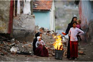 Syrian refugees warm themselves around a fire Dec. 3 in Ankara, Turkey. Martin Mark, right, executive director of Office of Refugees, Archdiocese of Toronto welcomes Canada’s pledge to bring in more refugees from the Middle East, but wished the government had consulted with refugee advocates before making its announcement.