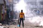 A man holds a weapon next to burning barricades during anti-government protests Feb. 17 in Port-au-Prince, Haiti. 