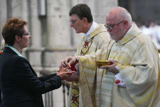 Cardinal Rainer Maria Woelki of Cologne, Germany, and Cardinal Reinhard Marx of Munich and Freising distribute Communion during Cardinal Woelki&#039;s installation Mass at the cathedral in Cologne Sept. 20, 2014.