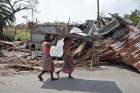 Residents carry tin sheets salvaged from the rubble of a damaged house in a village near Kolkata, India, May 22, 2020, in the aftermath of Cyclone Amphan.