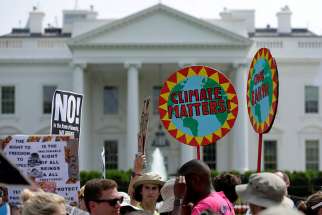 Protesters carry signs during the People&#039;s Climate March April 29 outside the White House in Washington. Donald Trump announced June 1 his decision “not to honour the U.S. commitment” to the Paris climate agreement.