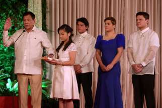 President Rodrigo Duterte takes the oath as his daughter Veronica holds the Bible during his presidential inauguration at the Malacanang Palace in Manila, Philippines. Duterte was sworn in as the 16th president of the Philippines.