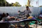 A man talks on his cellphone Aug. 6 next to an earthquake survivor outside a hospital on Lombok, Indonesia&#039;s popular tourist island. At least 91 people have been confirmed dead after the magnitude 7 earthquake Aug. 5, a week after another powerful quake killed more than a dozen people.