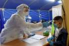 A nurse wears a protective suit while taking the temperature of a Palestinian boy in a special tent for pediatric and maternity COVID-19 patients at St. Joseph&#039;s Hospital in East Jerusalem April 16, 2020.