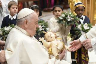 Pope Francis receives a statue of the baby Jesus that he will carry to the Nativity scene at the end of Christmas Mass in St. Peter&#039;s Basilica at the Vatican Dec. 24, 2023.