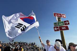 A young man from South Korea waves his country&#039;s flag before Pope Francis arrives for the closing Mass of World Youth Day at Tejo Park in Lisbon, Portugal, Aug. 6, 2023. At the end of Mass, the pope announced the next WYD will be held in Seoul, South Korea, in 2027.