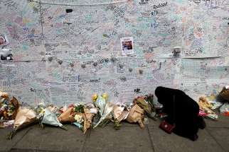 A woman kneels in prayer June 16 beside a message wall near a London apartment building destroyed in a June 14 fire. Church authorities in London confirmed that students from nearby Catholic schools are among the missing from the June 14 fire.