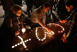 People light candles in the shape of a cross and heart in Republique square in Paris Nov. 14 in memory of victims of terrorist attacks.