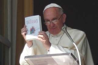 Pope Francis holds up a Bible as he promotes reading of the Bible during his Angelus delivered from the window of his studio overlooking St. Peter&#039;s Square at the Vatican Oct. 5, 2014. To help the church grow in love and faithful witness to God, Pope Francis has declared the third Sunday in ordinary time to be dedicated to the word of God.