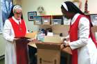 Sr. Gisele Goguen, left, and Sr. Juliet Onuoha prepare an order of communion hosts for a parish.