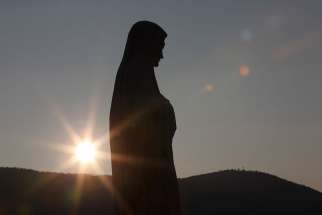 The sun sets behind a statue of Mary on Apparition Hill in Medjugorje, Bosnia-Herzegovina, in this 2011 file photo.