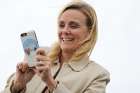 A woman with a smartphone cover featuring Pope Francis takes pictures as people await his on the airfield at Joint Base Andrews in Maryland Sept. 22, 2015.